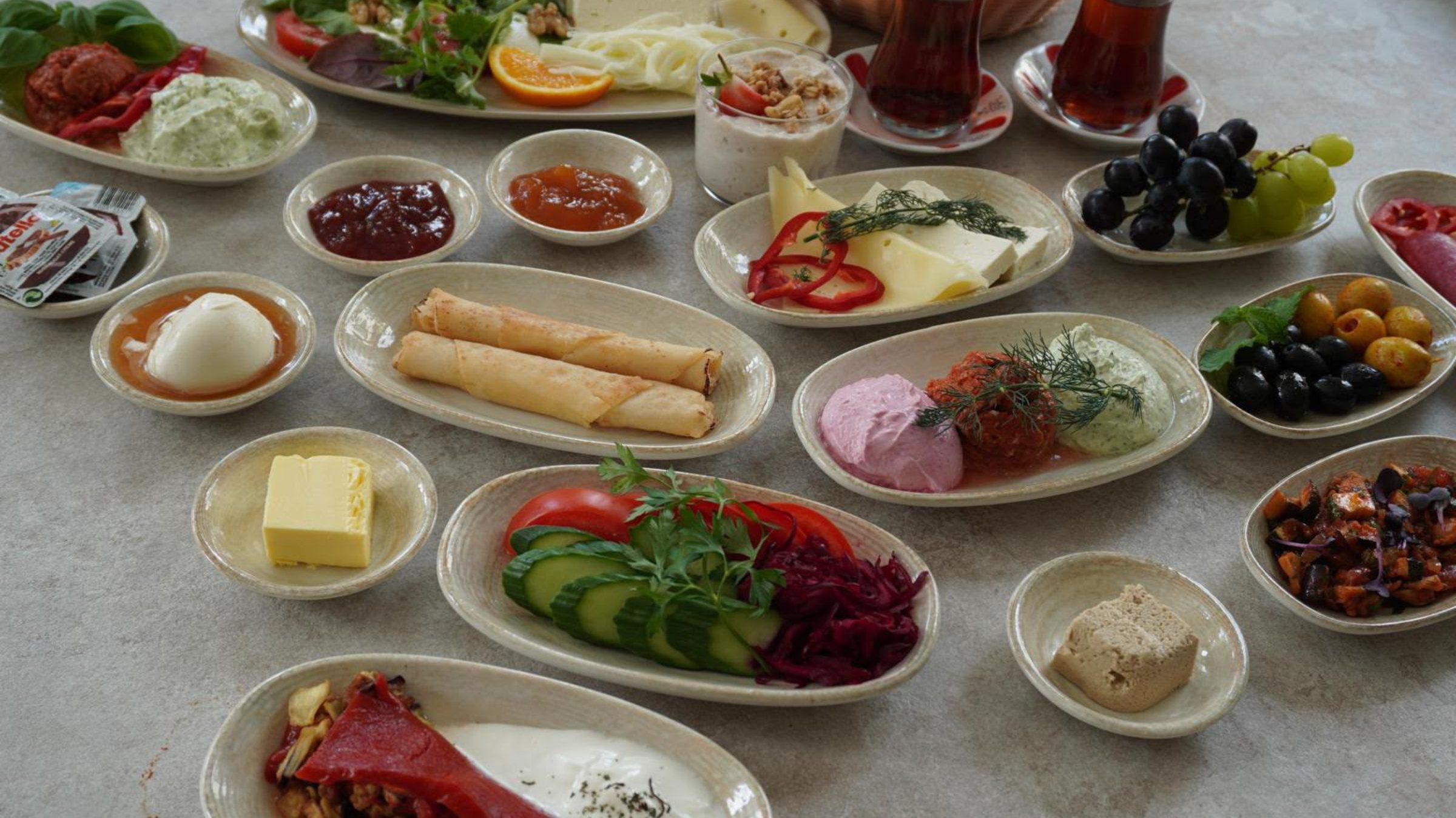 Reich gedeckte Serpme-Kahvaltı-Tafel mit Käse, Aufstrichen, Oliven, Obst und Çay